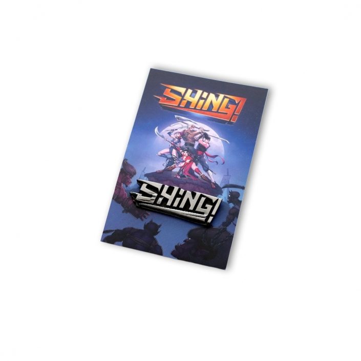 Pins gamingowy umieszczony na efektownej graficznie karcie z gry SHING!, wyprodukowany przez MCC Medale